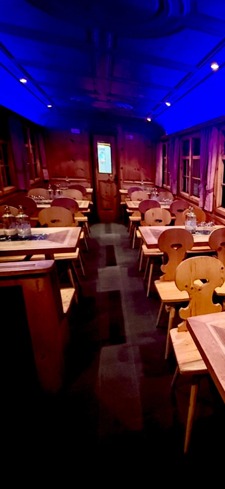 Tables set inside a wooden wagon under blue event lighting